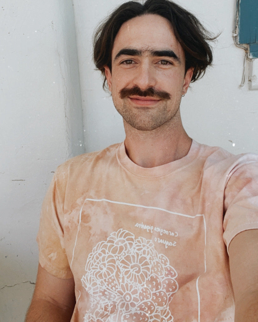 Photo of Trevor Mock smiling and wearing dusty rose pink shirt.